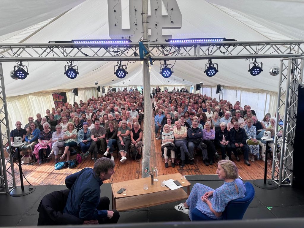 Ian Rankin in conversation with Jenny Colgan in front of a full marquee.