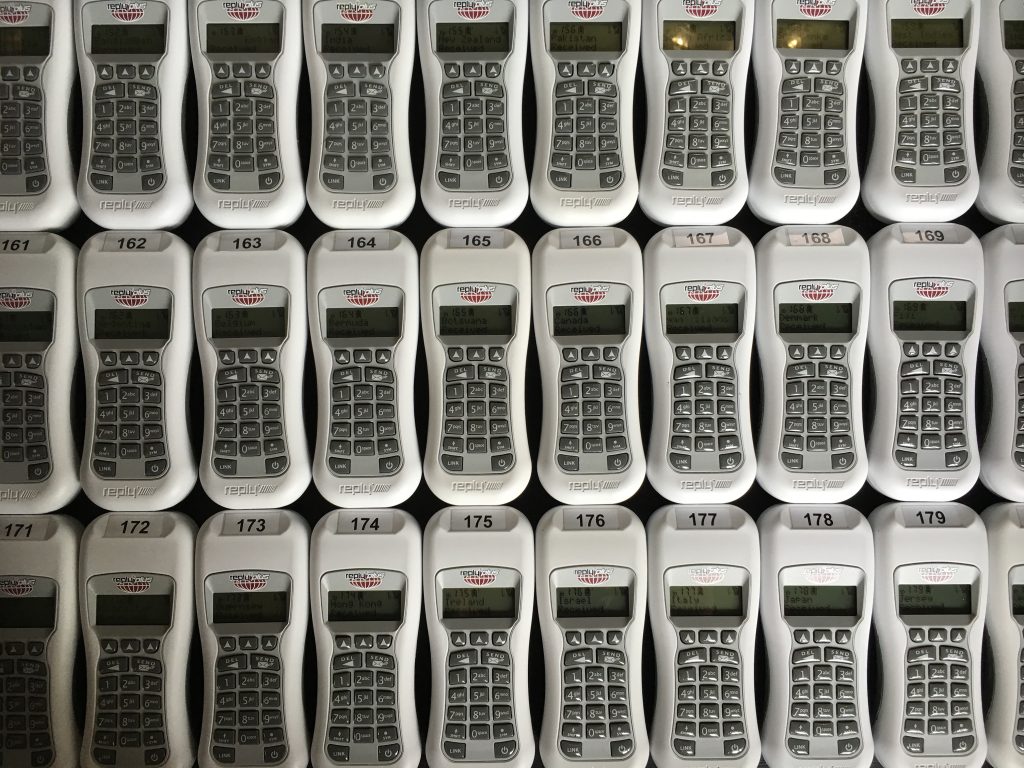 Voting keypads laid out on a table for for distribution.